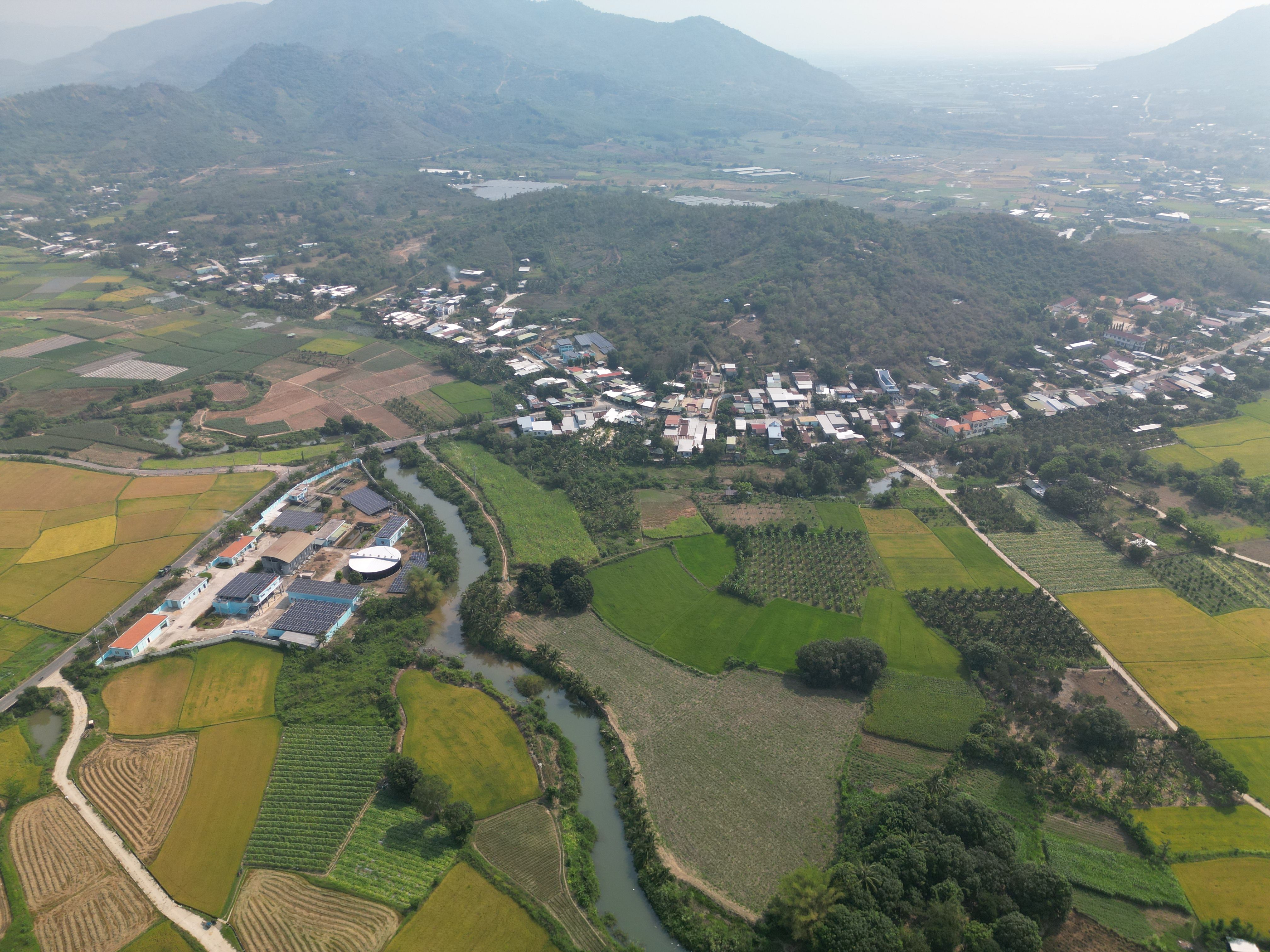 Scenic aerial view of lush Vietnamese countryside with fields, river, and village.