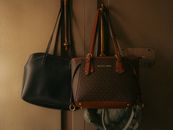 Stylish leather handbags hanging on a wall hook, showcasing elegant design and rich tones.