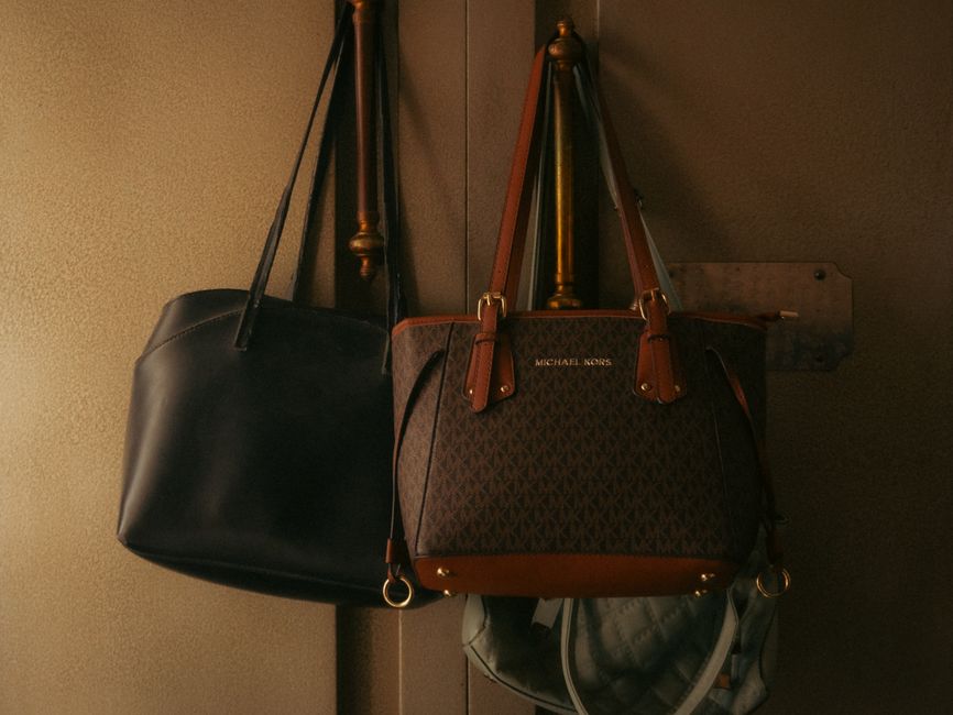 Stylish leather handbags hanging on a wall hook, showcasing elegant design and rich tones.