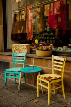 Colorful vintage chairs and table on a street, creating a warm and inviting look.