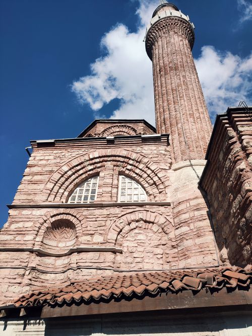 Free View of historic mosque with a towering minaret and intricate brickwork under a clear blue sky. Stock Photo