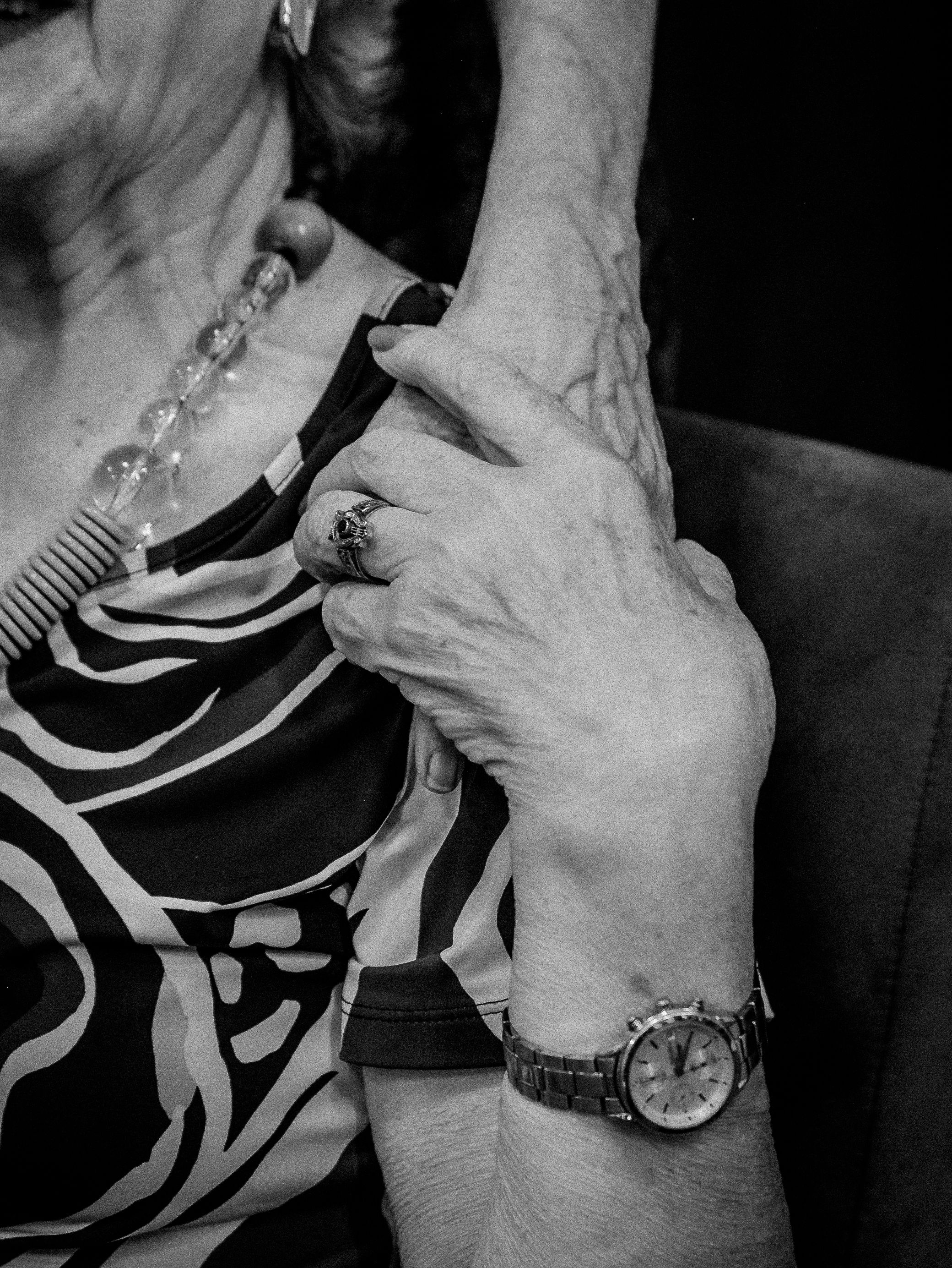 Black and white photo capturing an elderly woman's affectionate embrace and jewelry details.