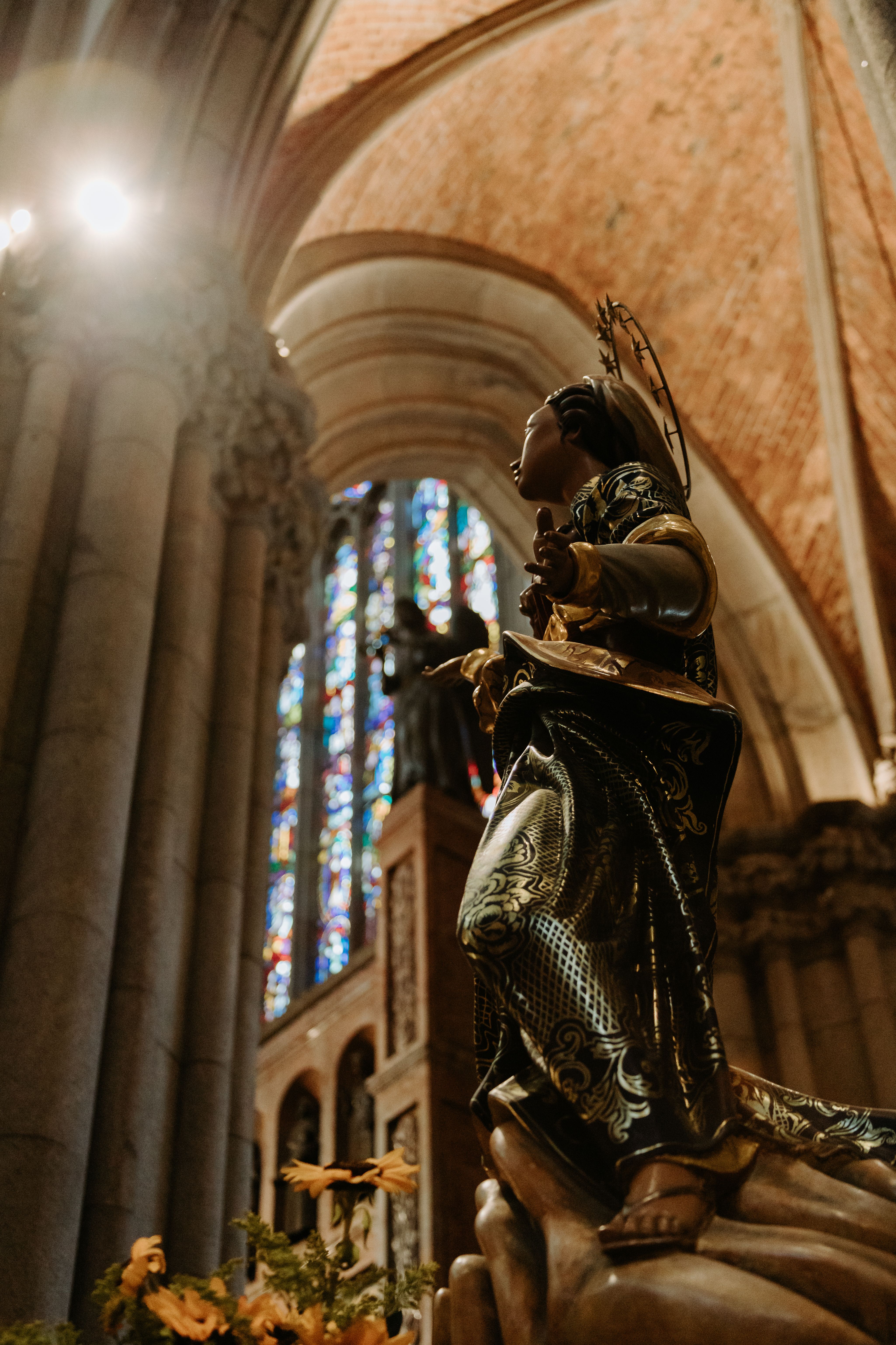 Stunning statue in historic cathedral with vivid stained glass windows and ornate architecture.