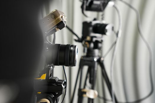 Close-up of professional video cameras on tripods in a studio setting.