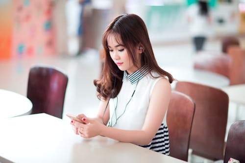 Free Woman Sitting on Chair Holding Smartphone Stock Photo