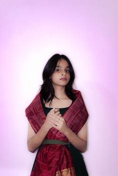 Elegant portrait of a woman in traditional South Asian attire against a pink backdrop.