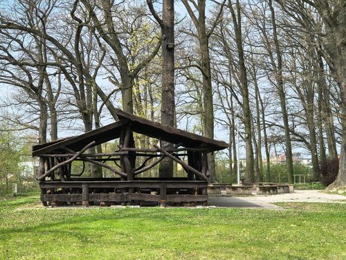 Free A rustic wooden shelter in a peaceful park surrounded by tall trees during spring. Stock Photo