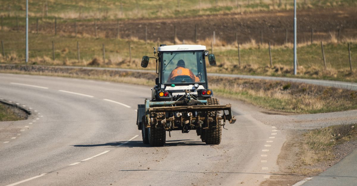 A tractor driving on a countryside road in Sweden, highlighting rural life and spring season.
