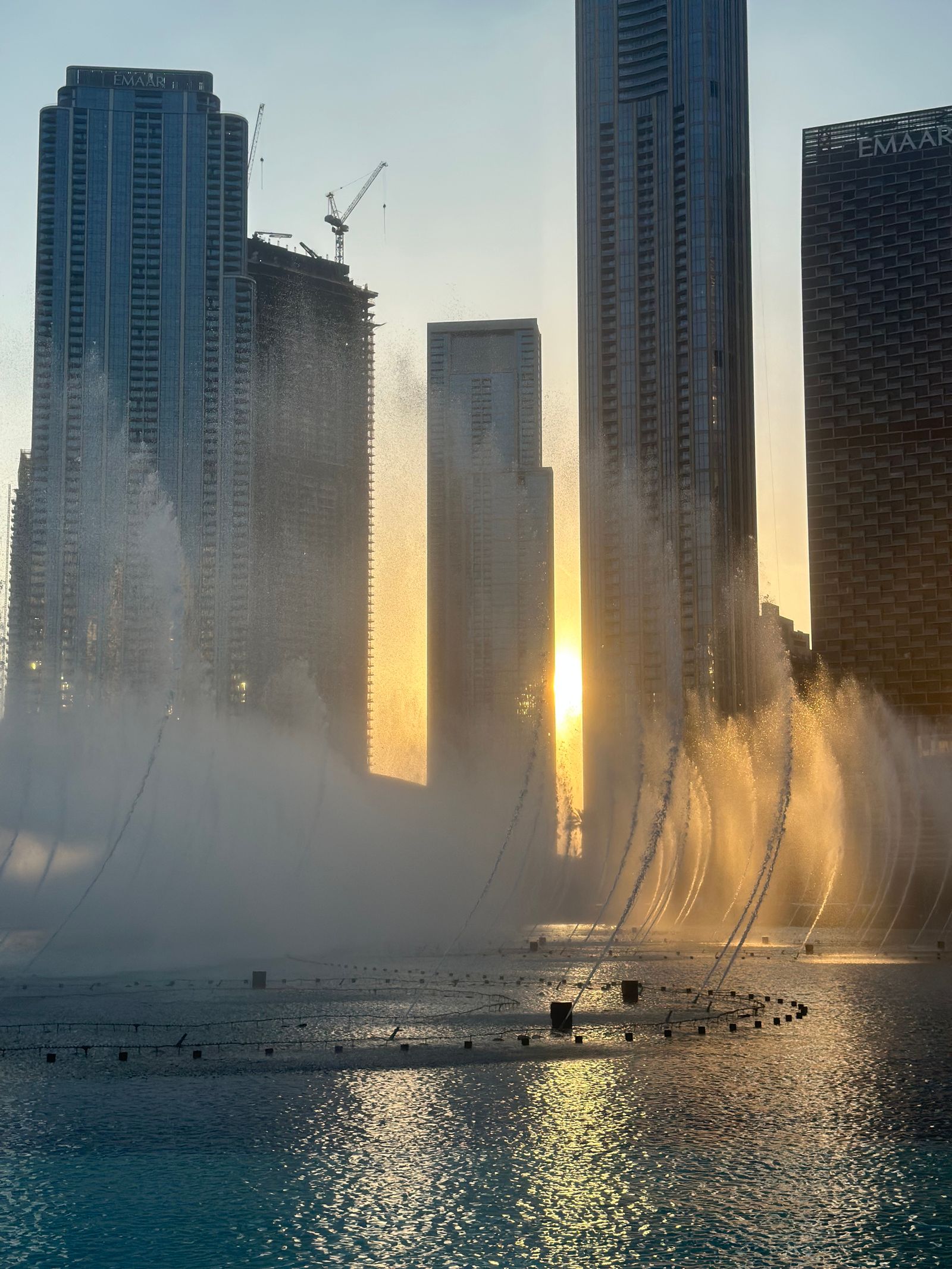 Dubai Fountain jets rising over Burj Lake at sunset in Downtown Dubai