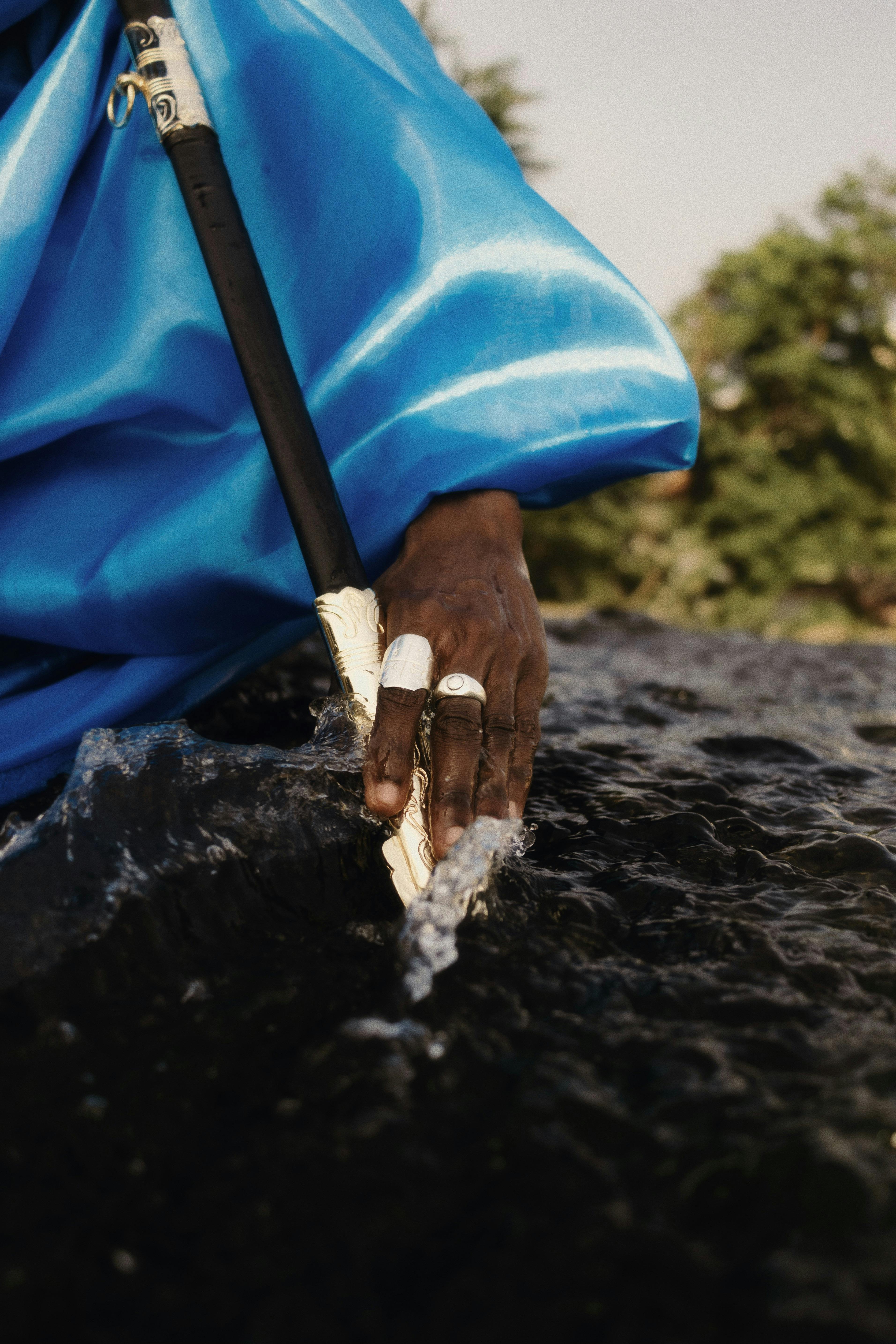 Close-up of a hand touching water with an ornamental stick in Nigeria.