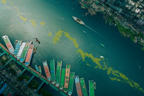 Free Stunning aerial view of boats docked in a vibrant urban harbor with eclectic colors and a bird flying over. Stock Photo