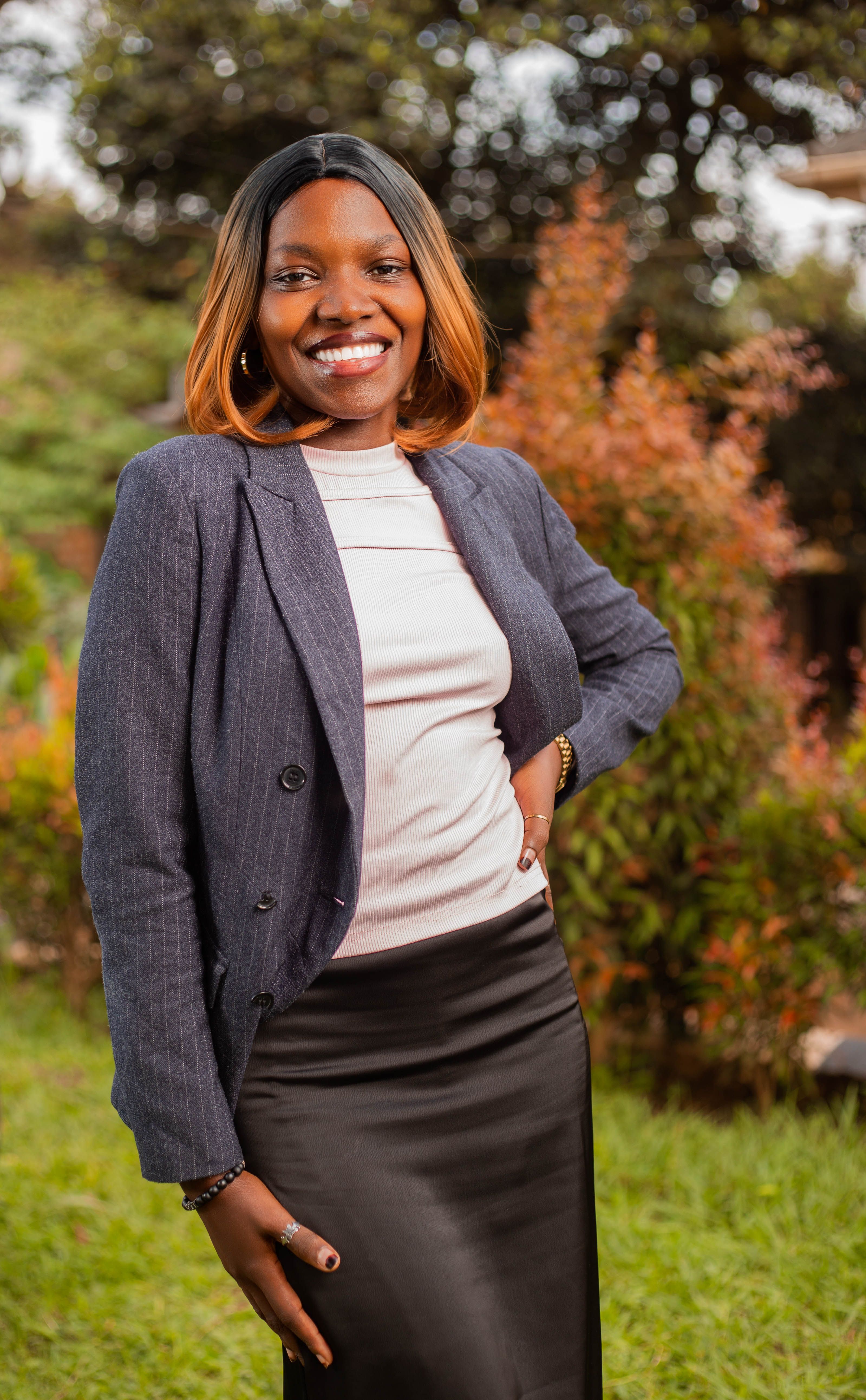 Portrait of a smiling businesswoman in professional attire with greenery background.