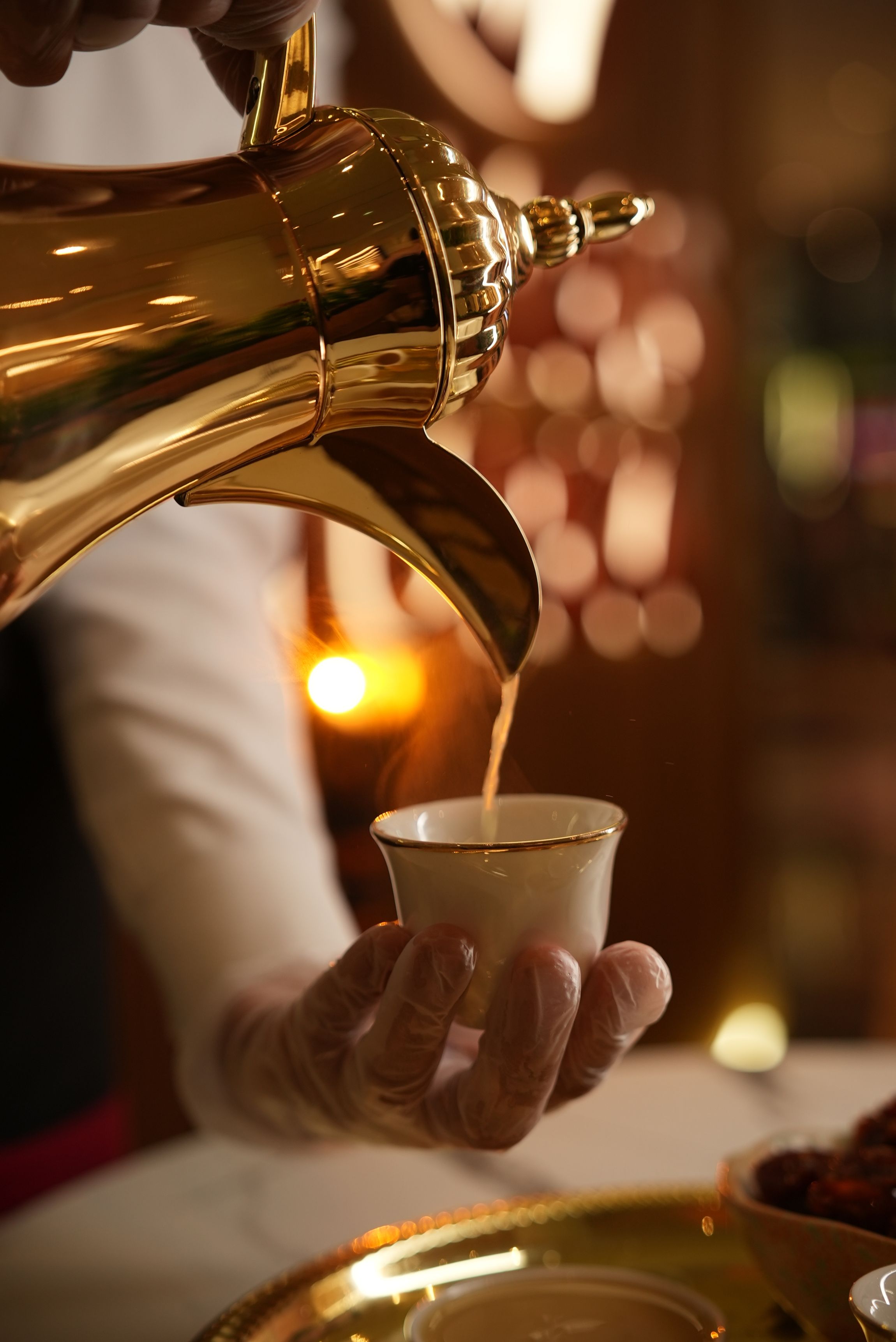 Arabic coffee being poured from a traditional golden pot during elegant service