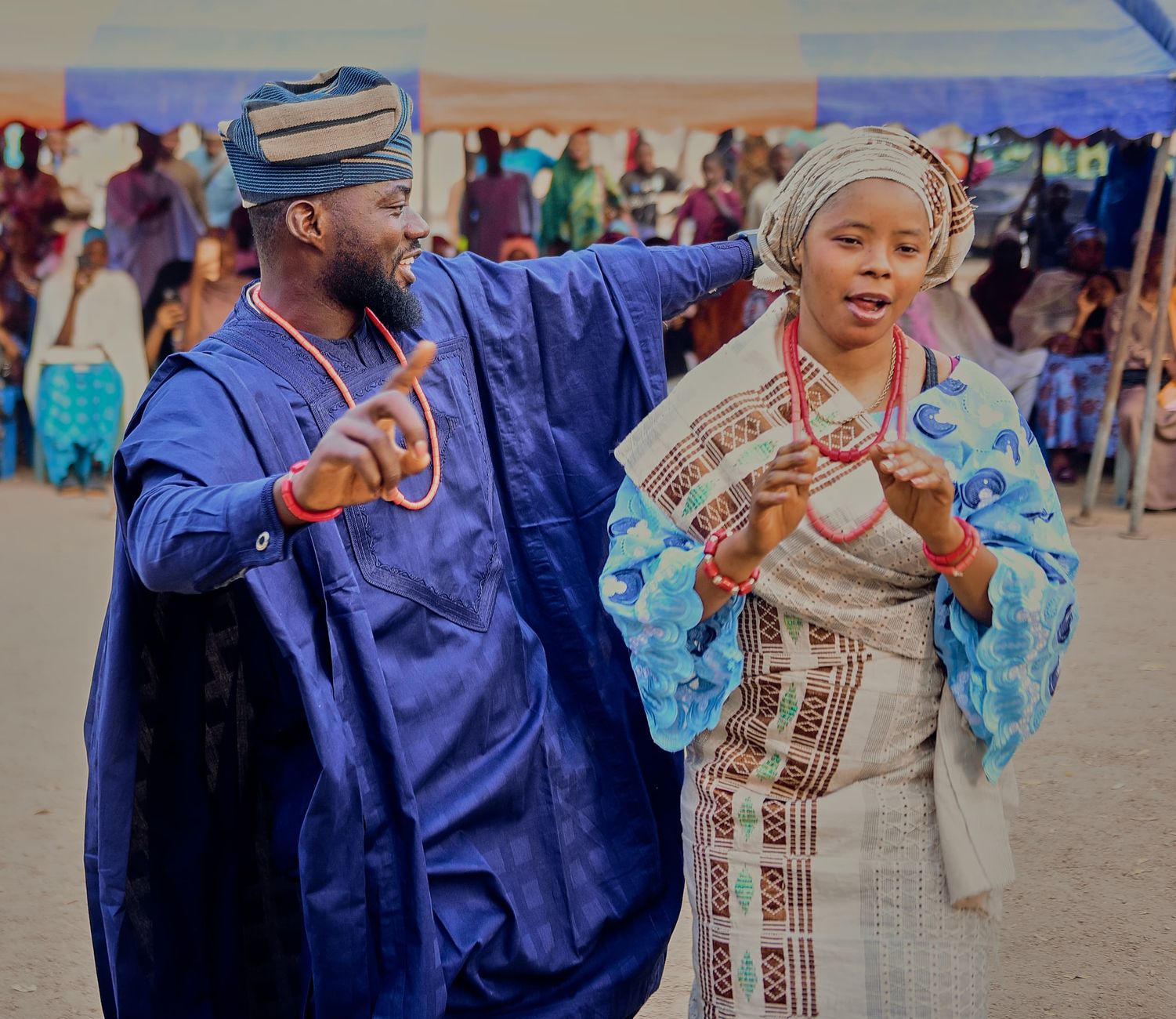 Vibrant celebration with African couple in colorful traditional outfits dancing joyfully outdoors.