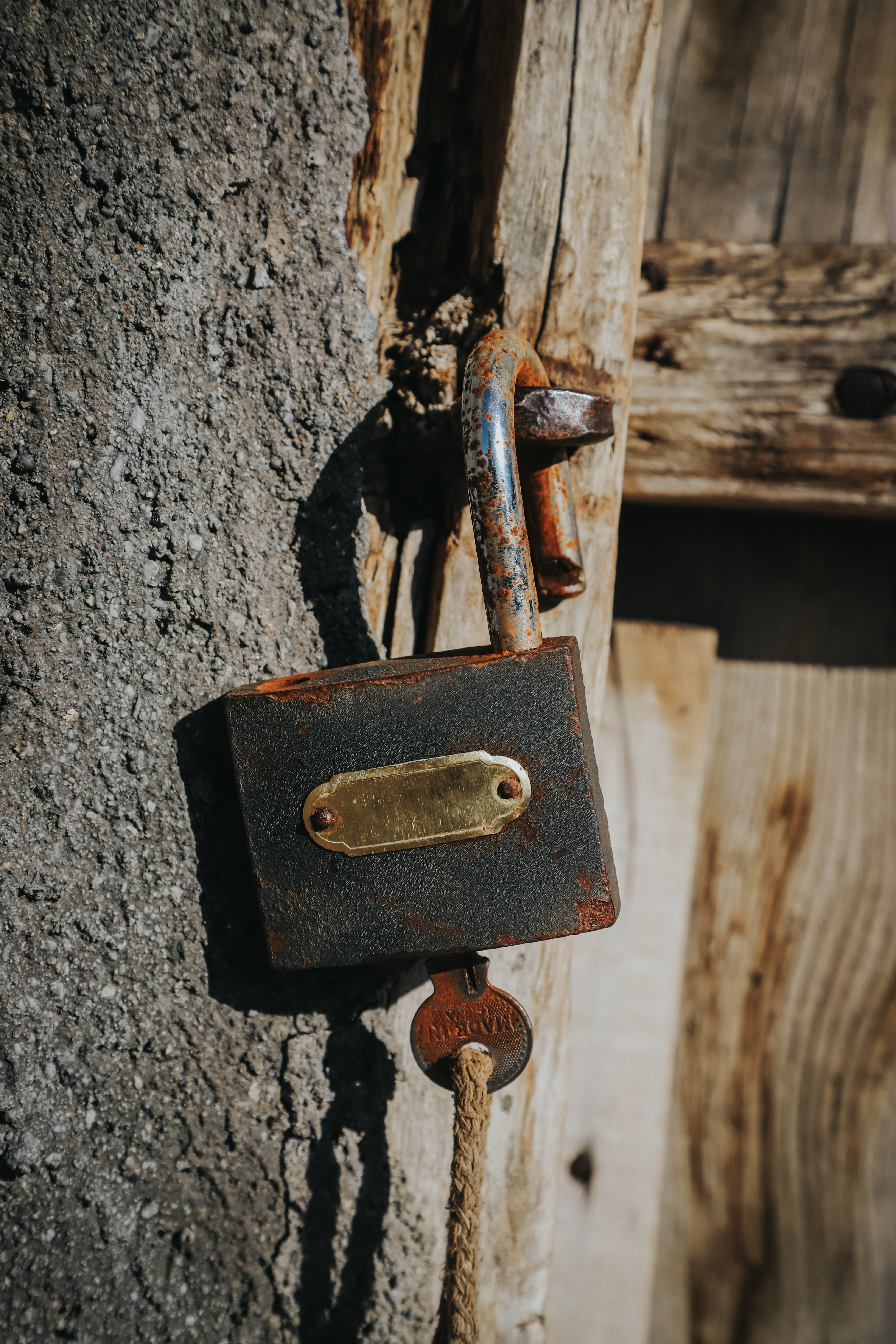 Fotomural Un candado oxidado cuelga de una puerta de madera desgastada, simbolizando la edad y el paso del tiempo.