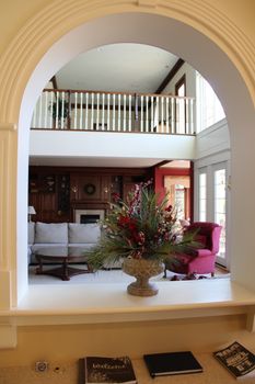 Elegant living room featuring a floral arrangement viewed through an arched opening, showcasing classic interior design.