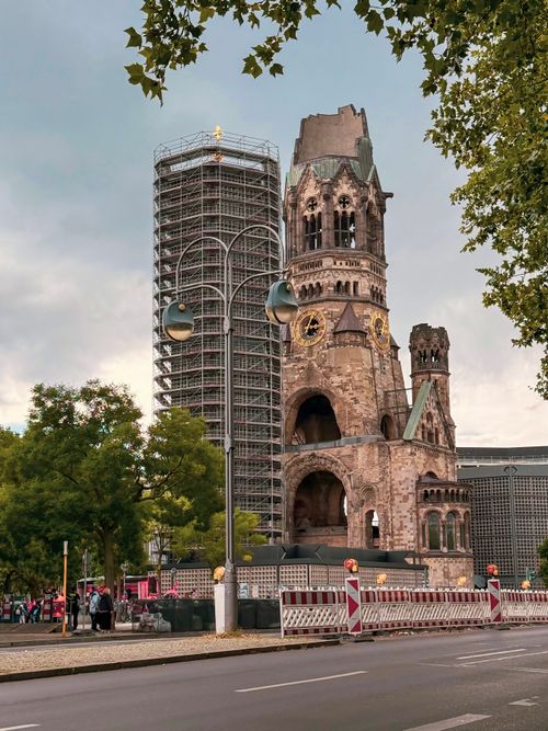 Free Historic Kaiser Wilhelm Memorial Church in Berlin with scaffolding and leafy foreground. Stock Photo