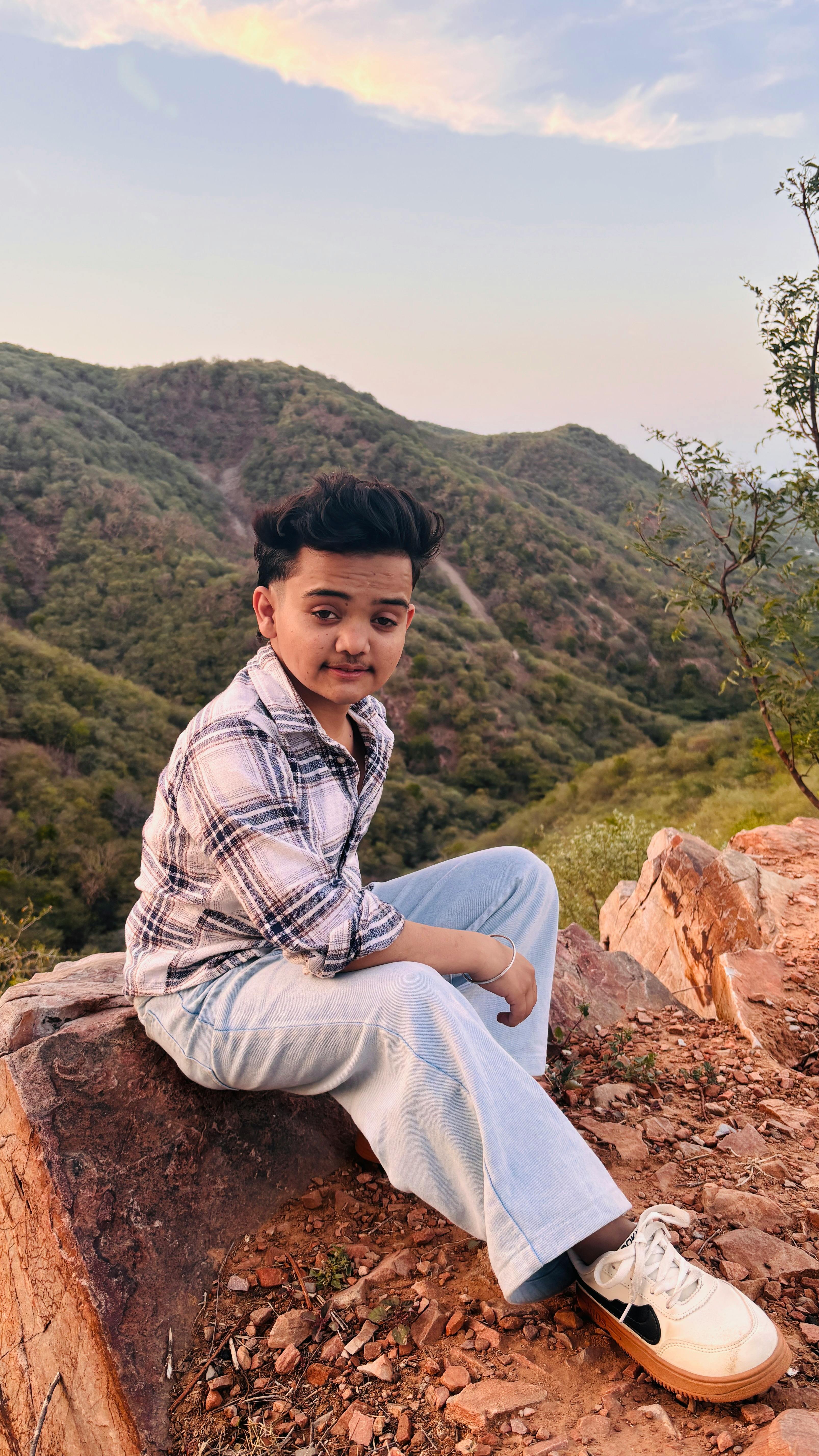 A person seated on a rock with scenic mountain view during sunset.