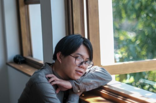 Free A young adult reflecting by the window in Da Nang, capturing serene moments. Stock Photo