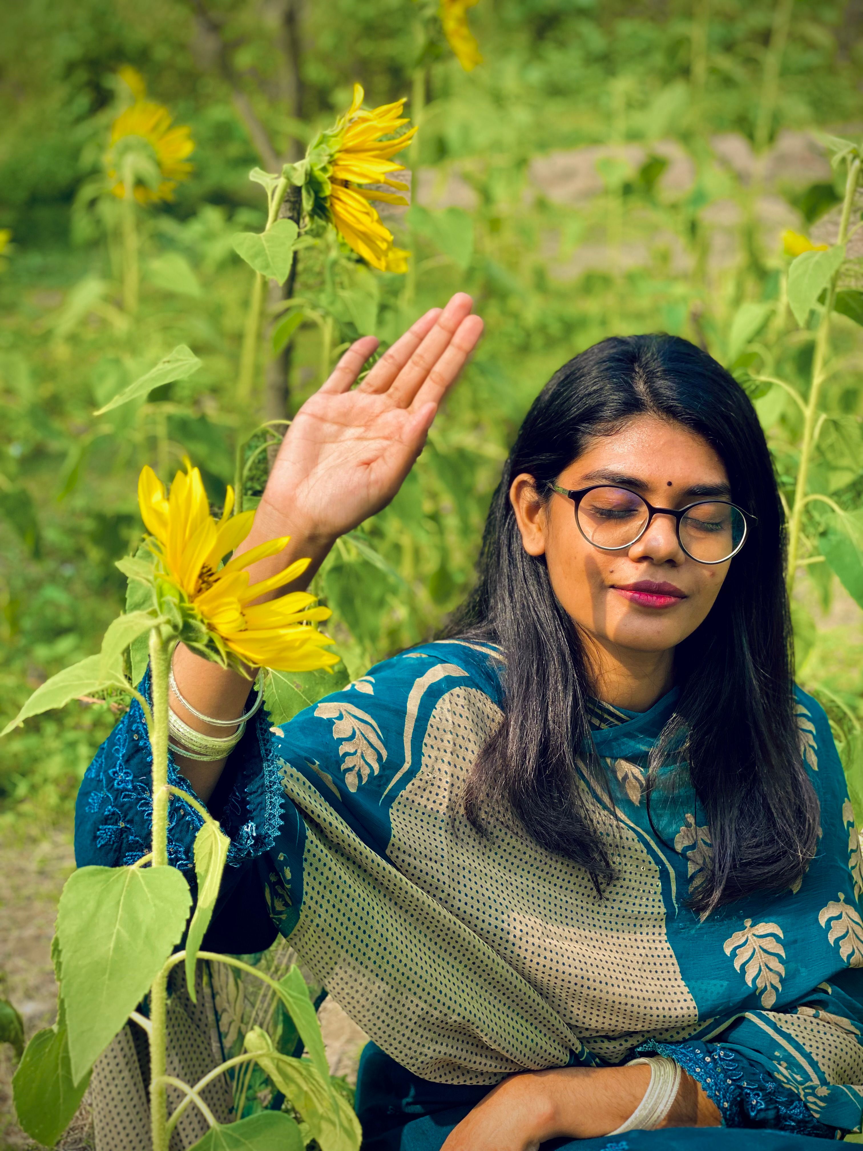 Woman meditating in sunflower field, embracing peace and nature vibes.