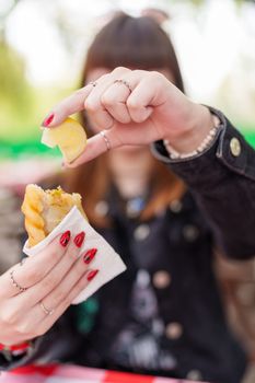 A person outdoors squeezing lemon on an empanada. Bright, colorful snack scene in Buenos Aires, Argentina.