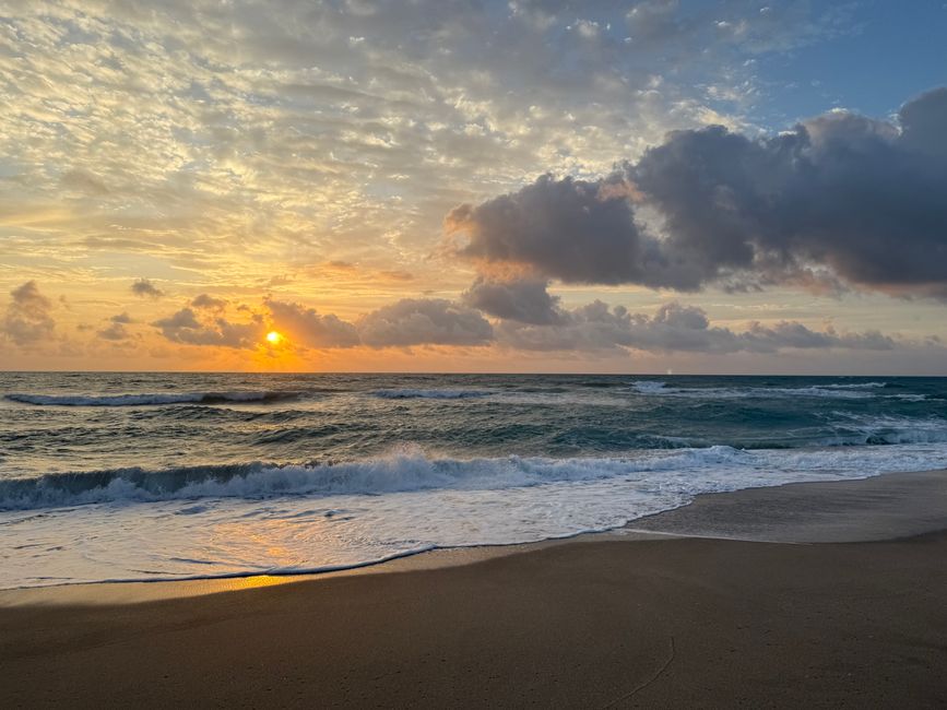 Beautiful sunrise over Jensen Beach, FL with waves crashing on the shore and vibrant clouds.
