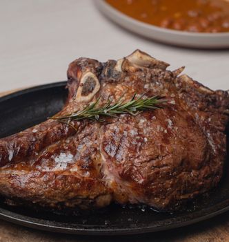 Delicious grilled ribeye steak seasoned with salt and rosemary on a cast iron skillet.
