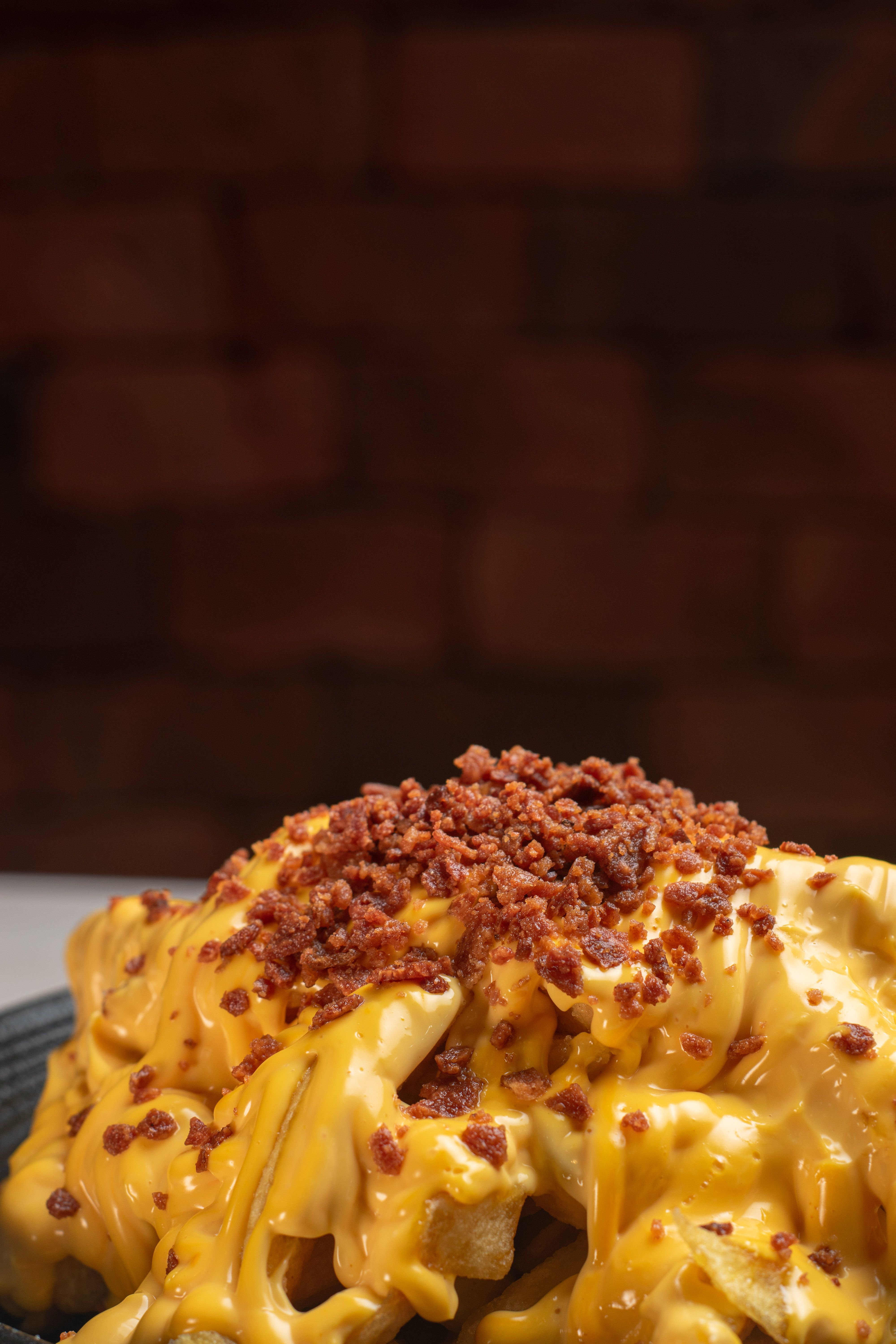 Arti.tic - Delicious golden fries loaded with melted cheese and crispy bacon bits, perfect for a savory treat.