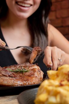 A happy woman savoring a deliciously cooked steak with sides in a cozy restaurant.