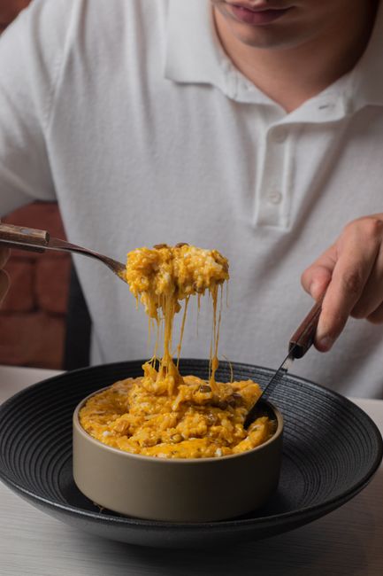 A bubbling chicken and rice casserole in a white baking dish, topped with melted cheddar and golden cracker crumbs, with a serving spoon lifting out a portion showing tender rice and diced chicken.