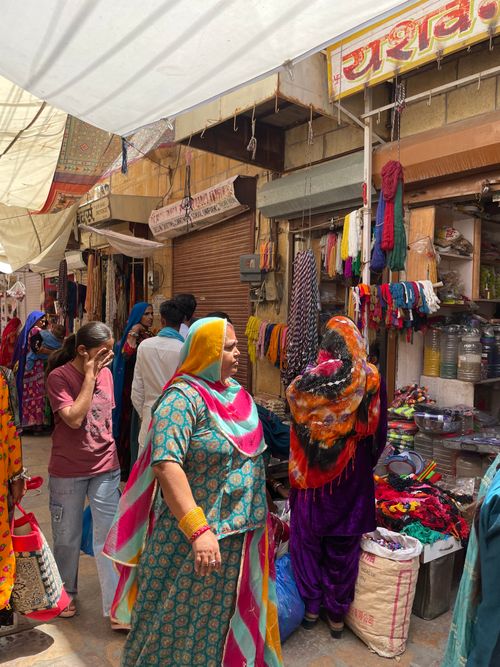 Free Bustling street market in Jaisalmer, India with colorful fabrics and local shoppers. Stock Photo