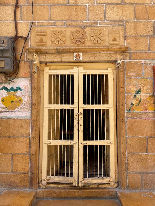 Free An intricate yellow door set in a sandstone wall in Jaisalmer, India, showcasing local artistry. Stock Photo