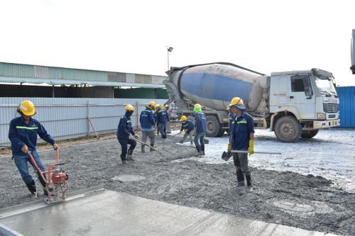 Free Workers in safety gear pouring concrete outdoors with a cement mixer truck. Stock Photo
