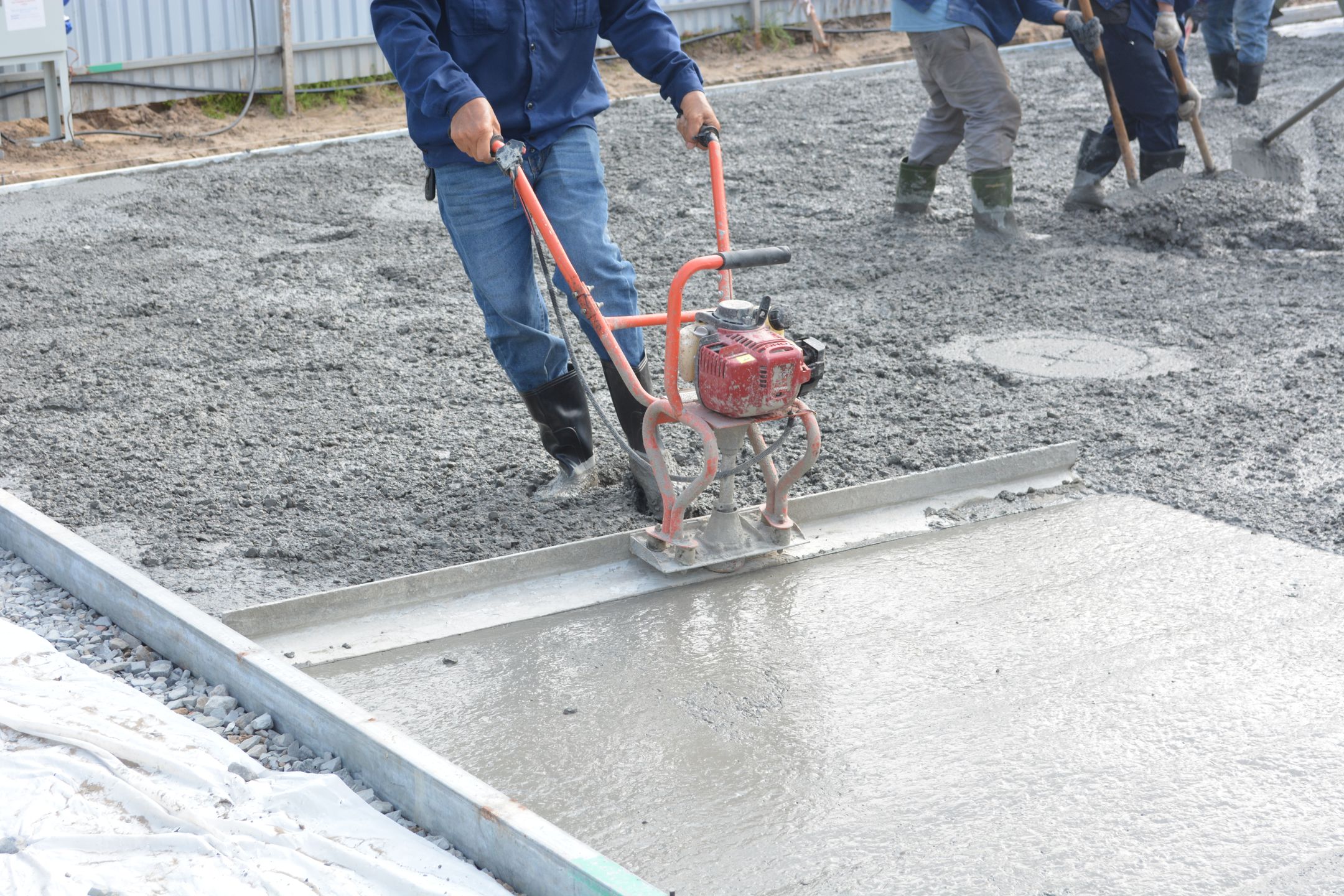 Crew using power tools to level fresh concrete