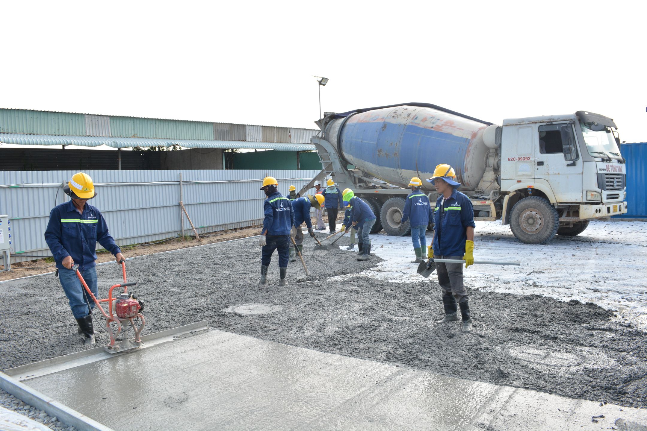 Crew pouring and leveling a concrete pad