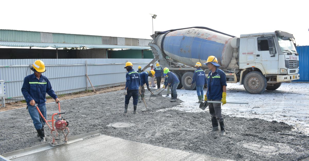 Team of workers pouring cement from a mixer truck on a construction site, ensuring proper leveling.