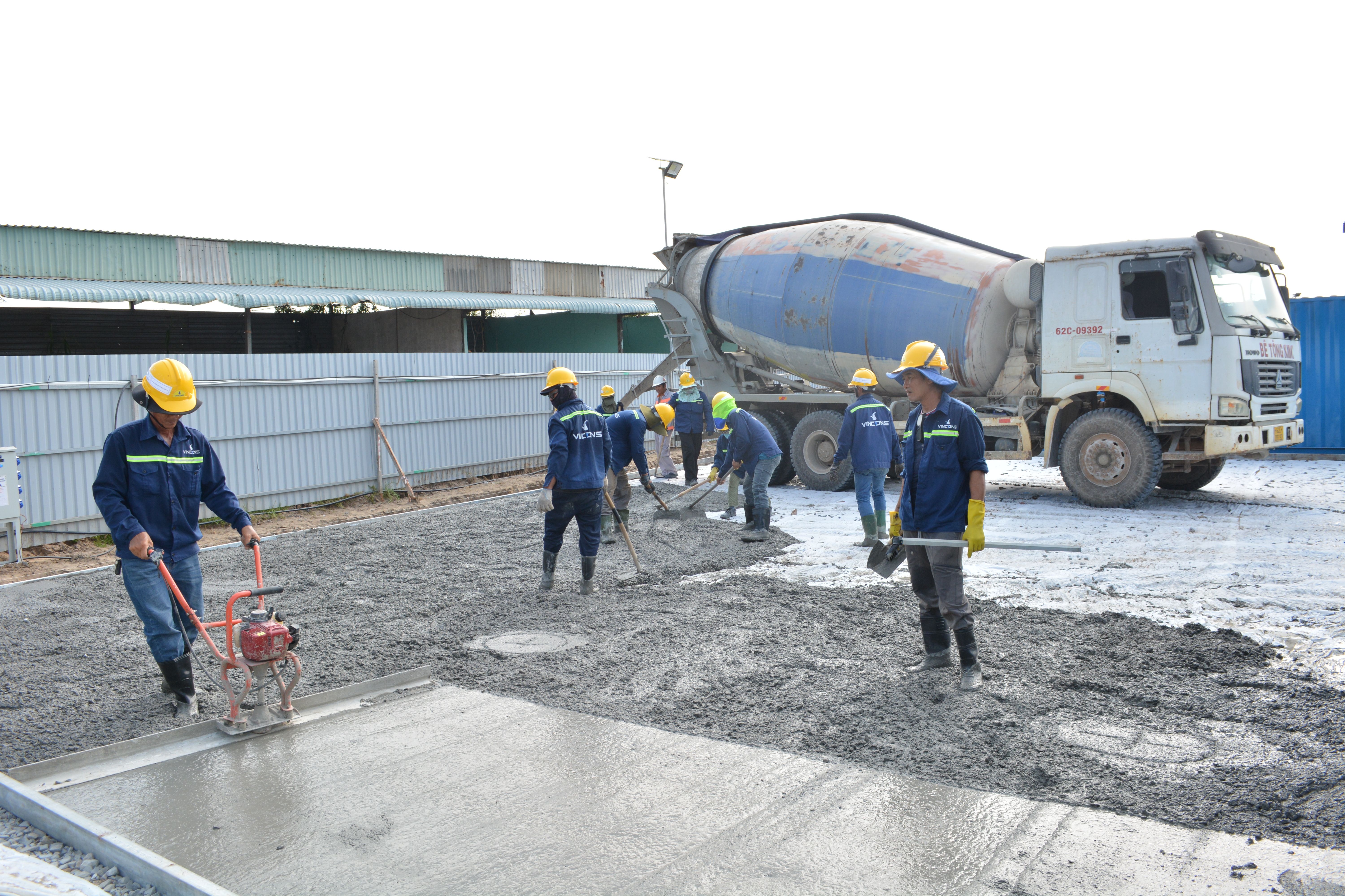 Team of workers pouring cement f rom a mixer truck on a construction site, ensuring proper levelling