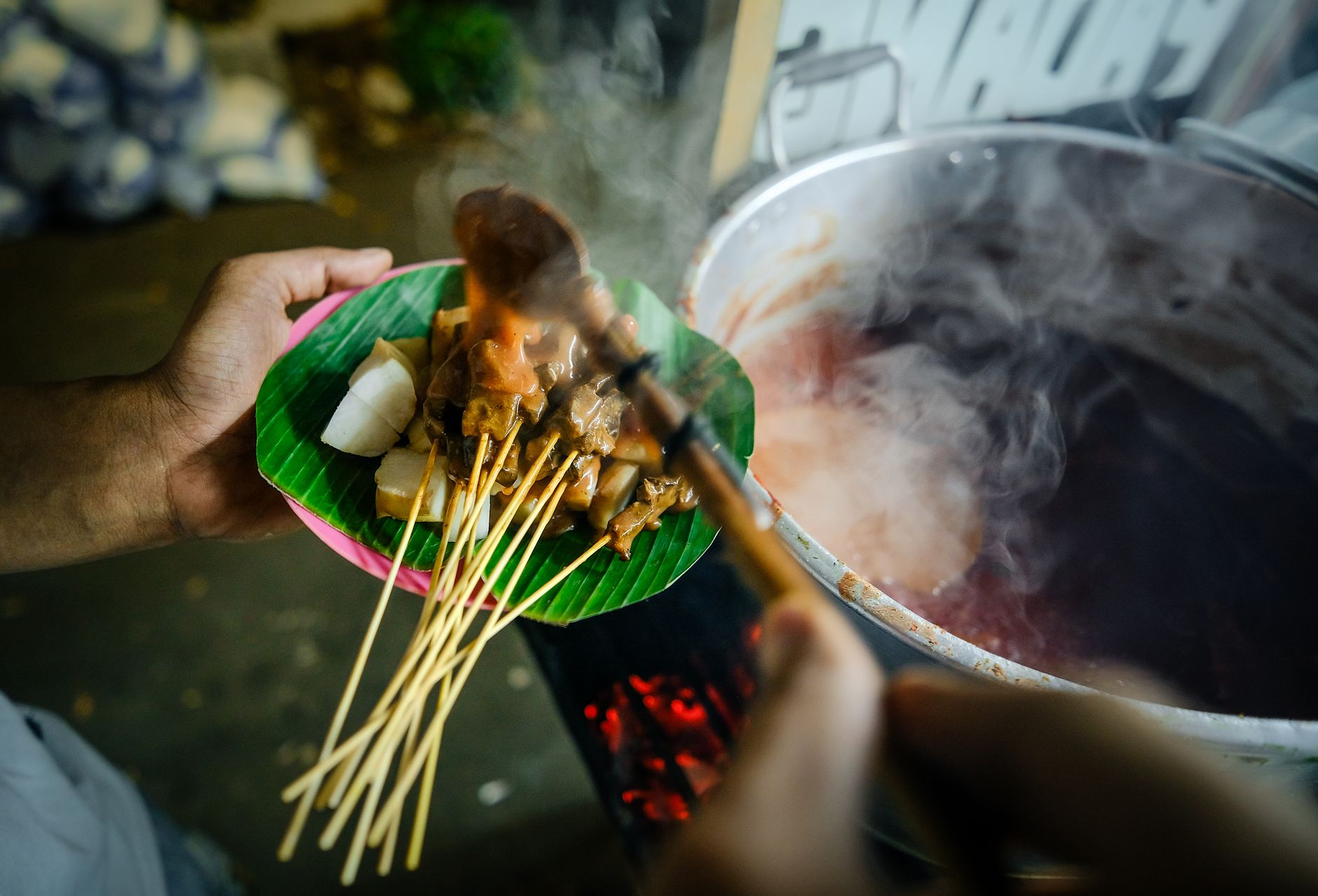 Savor authentic Indonesian satay with peanut sauce on a vibrant banana leaf.