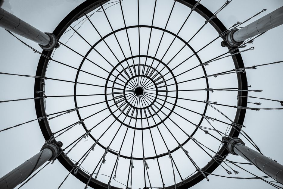 Artistic monochrome shot of a circular metal structure taken from below, highlighting design elements.