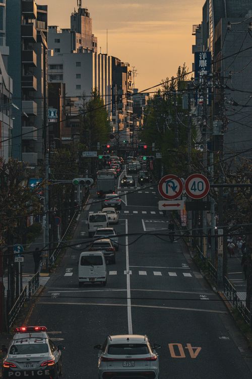 Free Busy urban street in Tokyo at sunset with traffic and buildings lining the road. Stock Photo