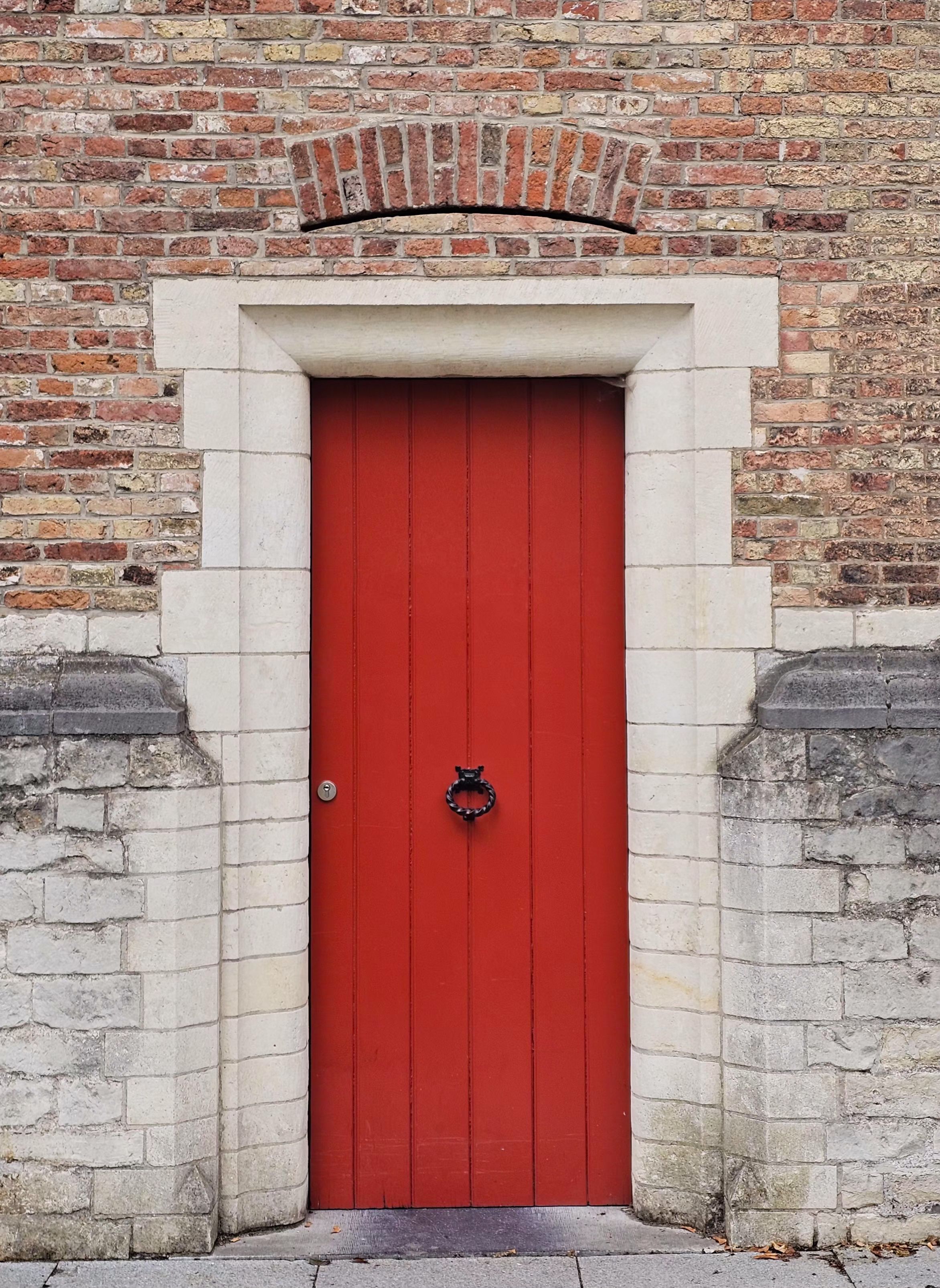 A vibrant red door set in a stone and brick wall, offering a quaint charm.