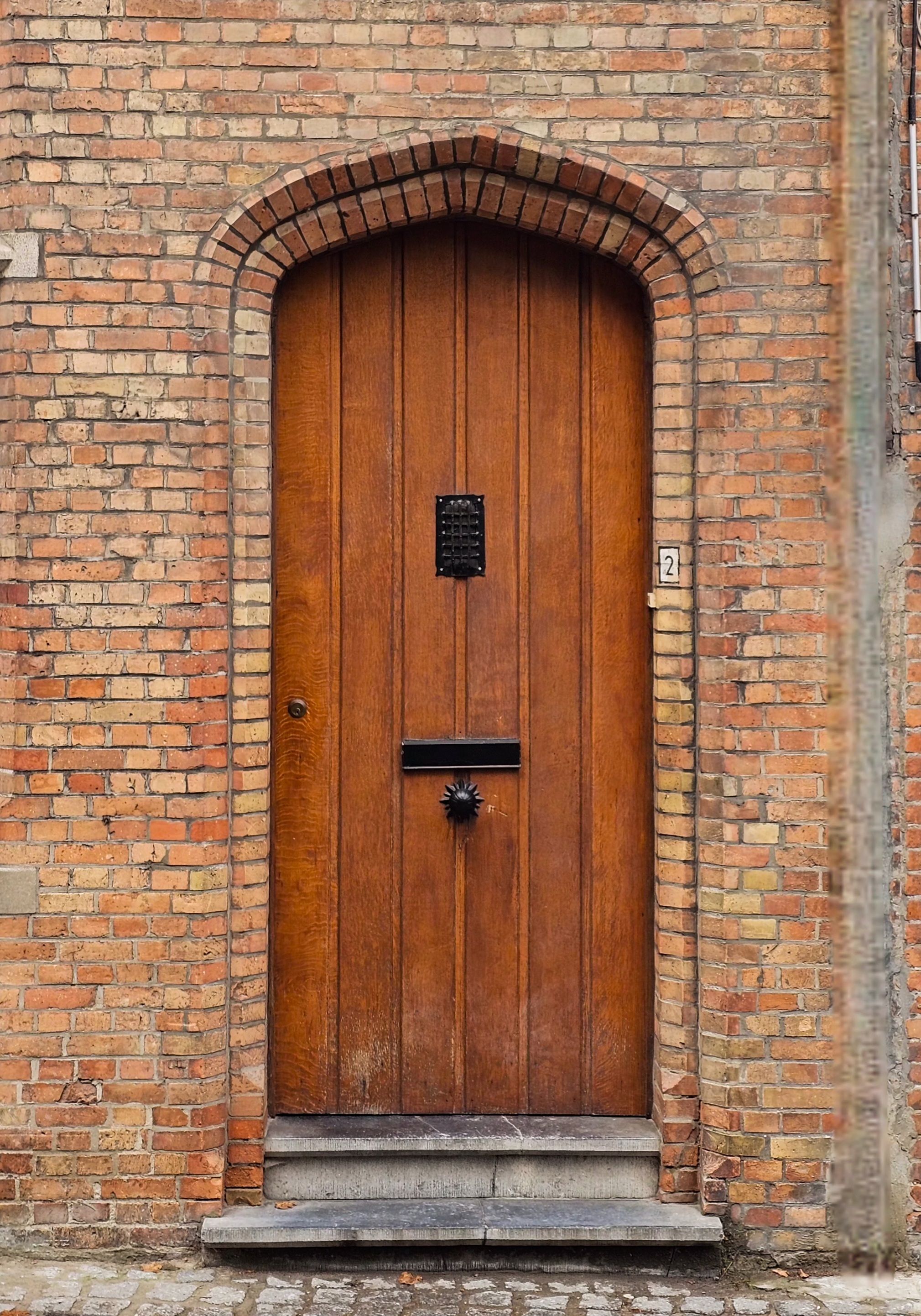 A classic wooden door set in a brick wall with vintage features and ornate detailing.