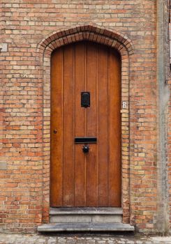 A classic wooden door set in a brick wall with vintage features and ornate detailing.