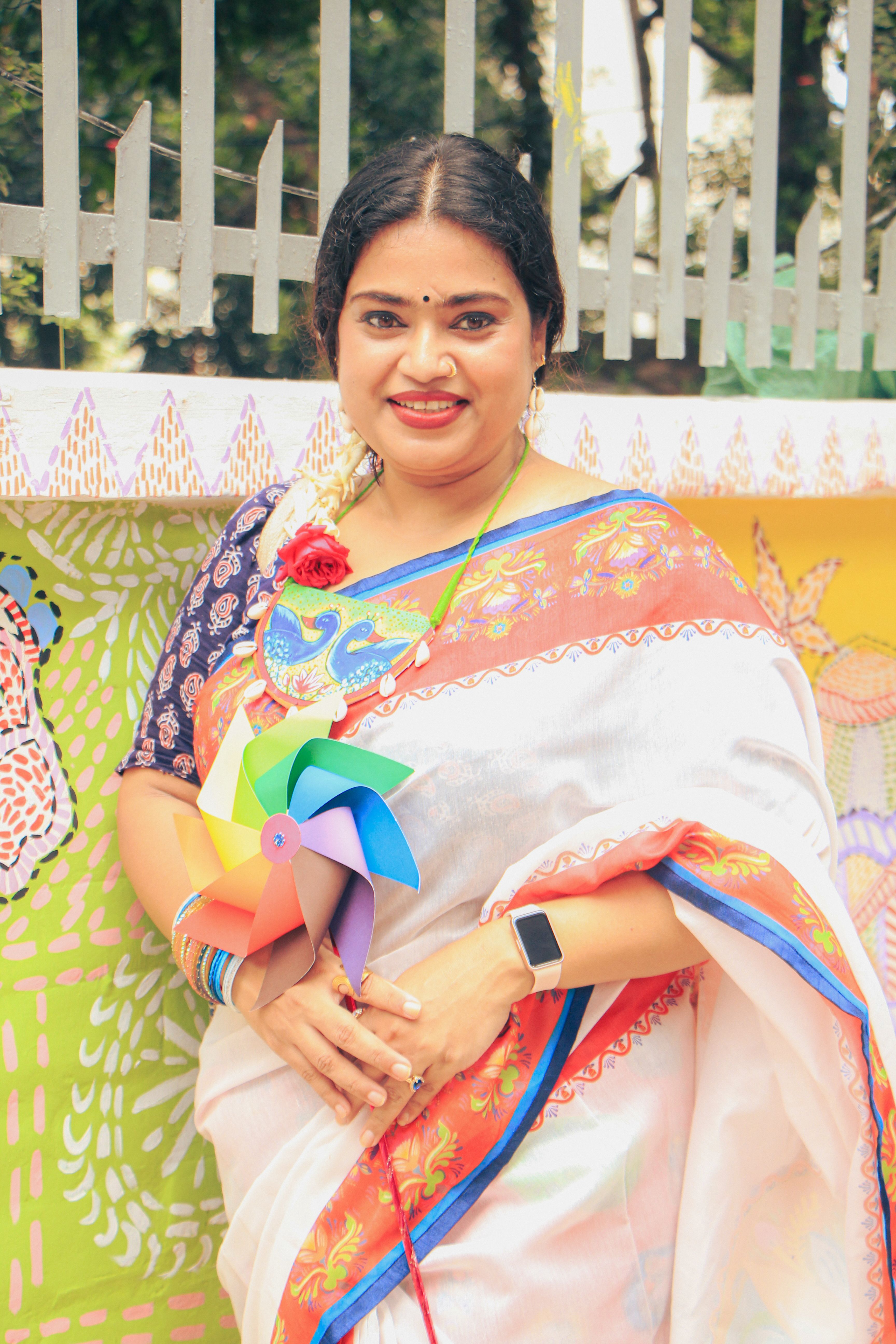 South Asian woman celebrating in colorful traditional saree outdoors, enjoying cultural festival.