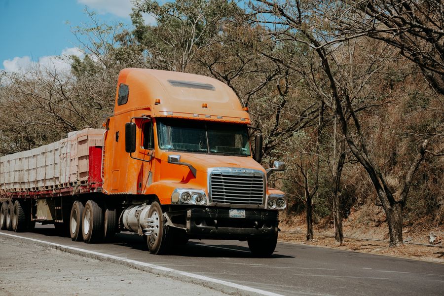 Orange freightliner semi truck on the highway