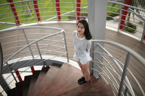 Woman Standing on Brown Wooden Spiral Staircase