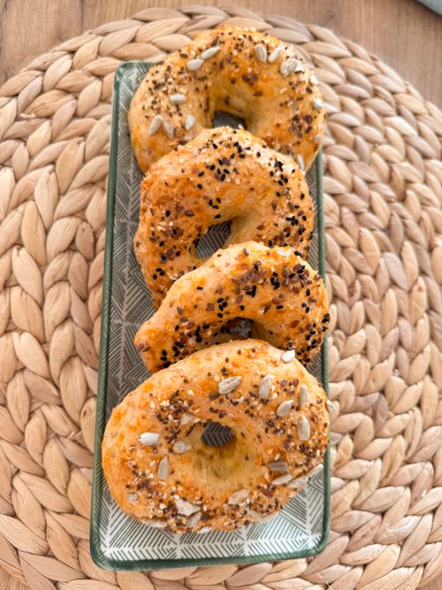 Free Savory homemade bagels topped with mixed seeds elegantly arranged on a stylish tray. Stock Photo