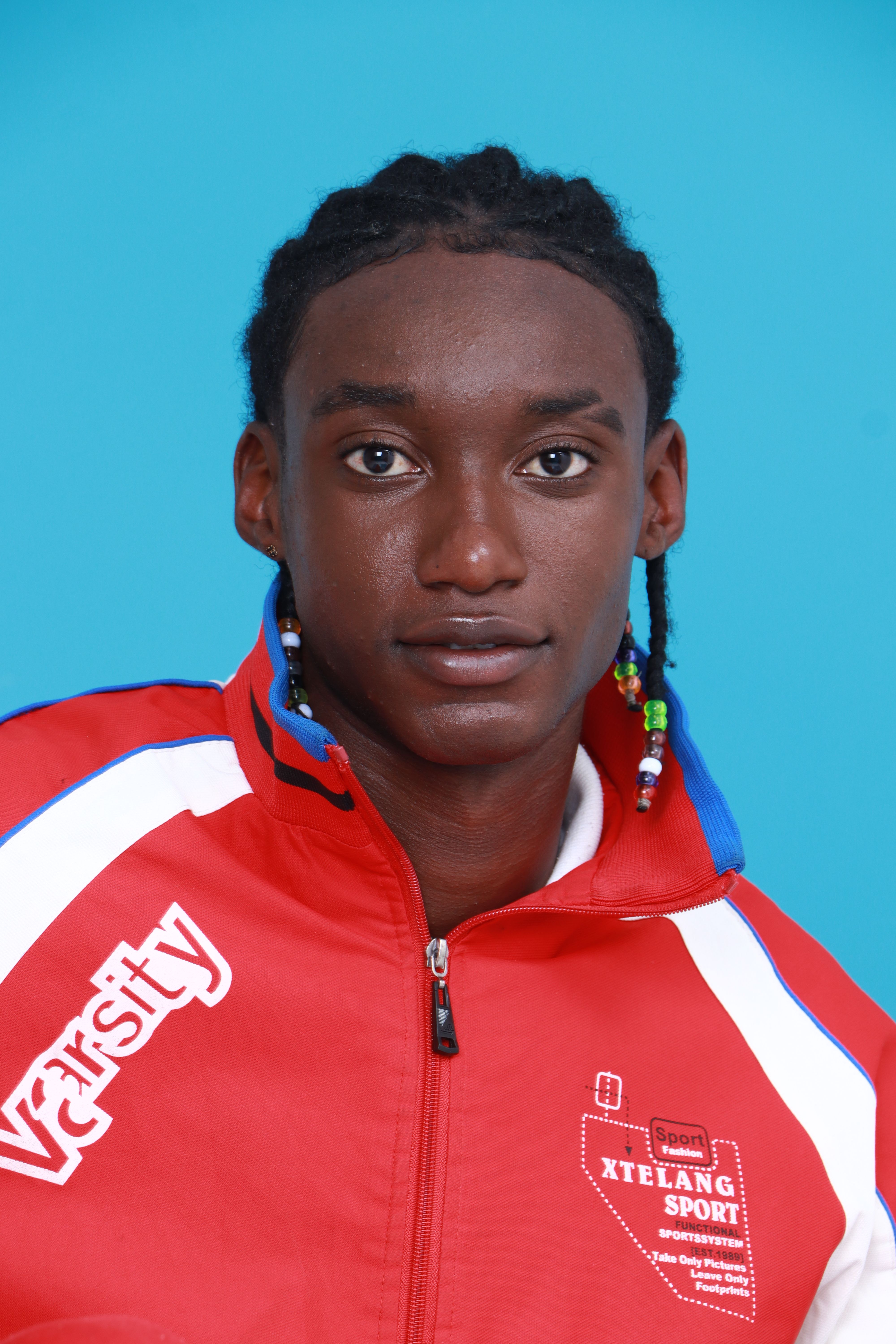 Vibrant portrait of a young athlete wearing a red sports jacket against a blue background.