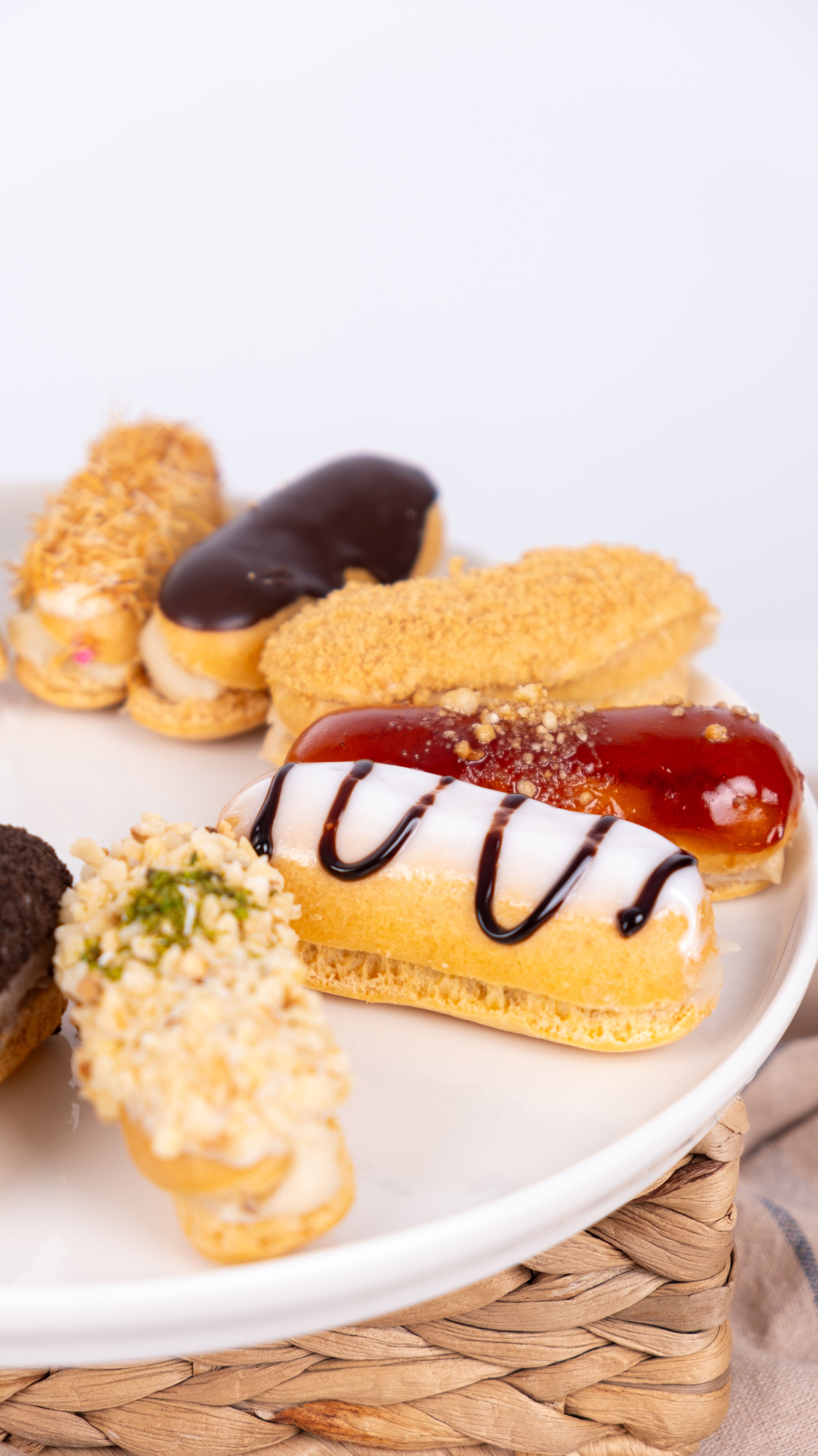 A variety of colorful eclairs with different toppings beautifully arranged on a plate.