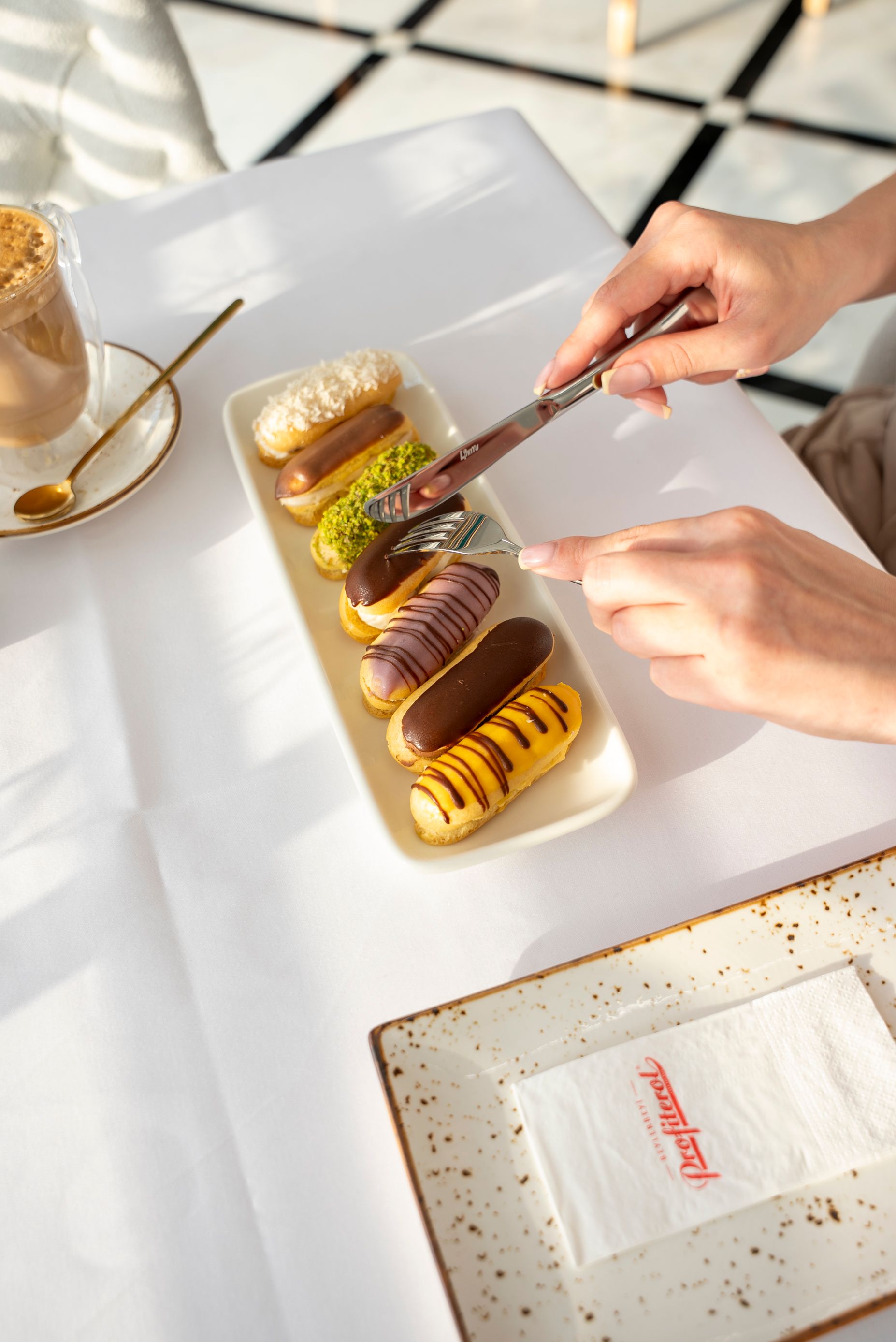 Stylish composition of gourmet eclairs with a latte in a bright cafe setting.